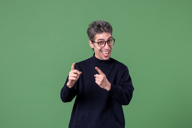 Retrato de hombre joven genio vestido casualmente en foto de estudio feliz en la pared verde