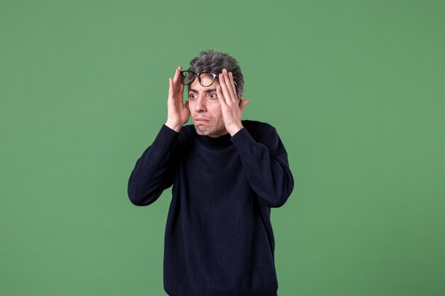 Retrato de hombre joven genio vestido casualmente en foto de estudio en la pared verde