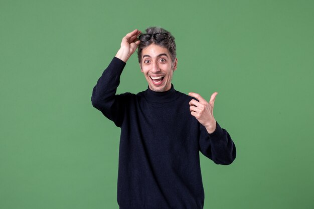 Retrato de hombre joven genio vestido casualmente en foto de estudio en la pared verde