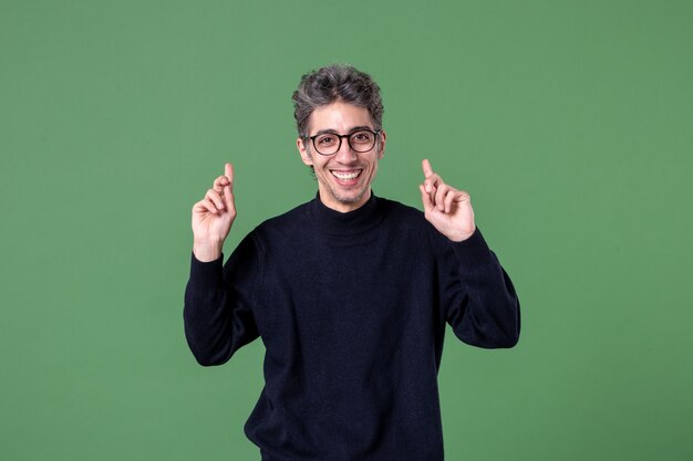 Retrato de hombre joven genio vestido casualmente en foto de estudio sonriendo en la pared verde