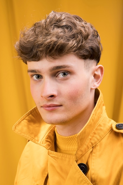 Retrato de hombre joven y guapo en un escenario amarillo