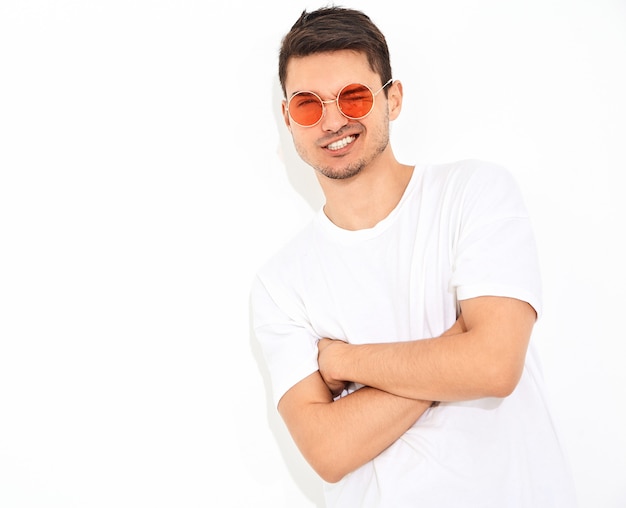 Retrato de hombre joven y guapo modelo vestido con ropa de jeans y camiseta en gafas de sol posando. Brazos cruzados