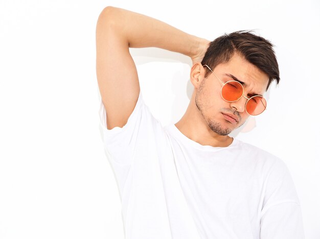 Retrato de hombre joven y guapo modelo vestido con ropa de jeans y camiseta en gafas de sol posando. Tocando su cabeza
