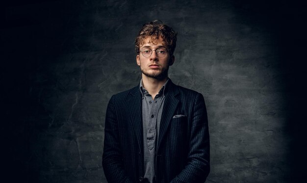 Retrato de un hombre joven y guapo con el pelo rizado vestido con una chaqueta y anteojos.