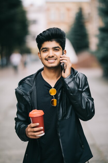 Retrato de hombre joven hablando por teléfono y caminando por la calle