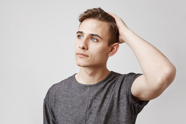 Foto gratuita retrato de hombre joven con hermosos ojos azules tocando su cabeza.