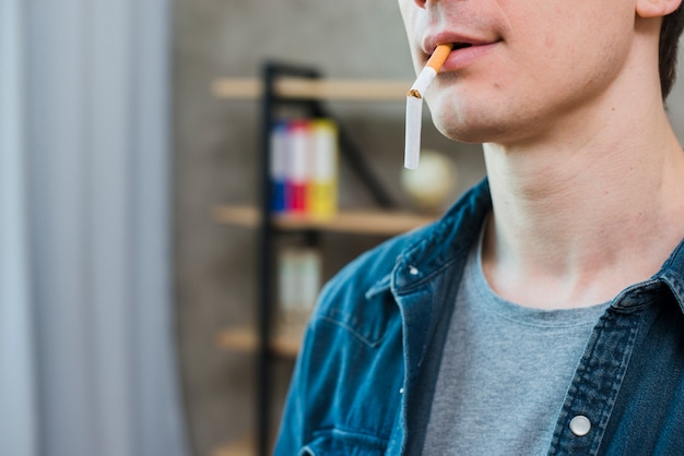 Foto gratuita retrato de hombre joven llevando cigarrillos rotos en la boca