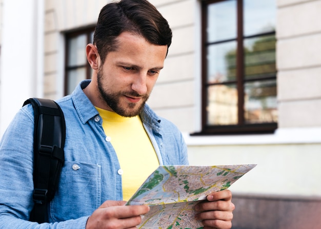 Retrato de hombre joven mirando el mapa durante el viaje