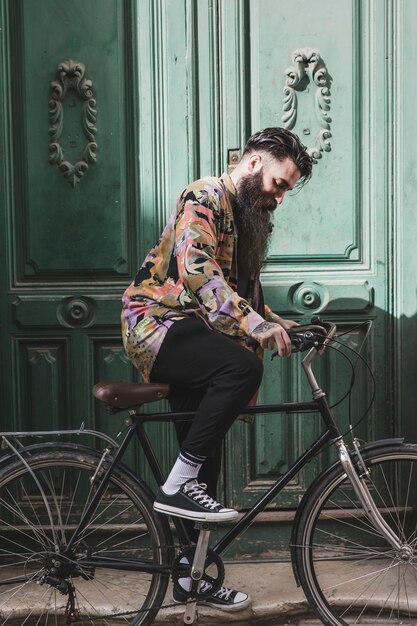 Retrato de un hombre joven de moda que monta la bicicleta