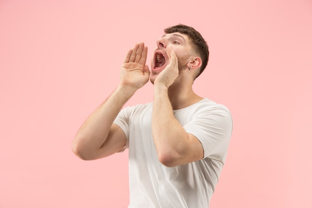 Retrato de hombre joven de moda sobre fondo rosa. Expresión emocional.