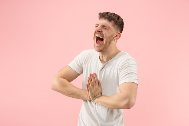 Retrato de hombre joven de moda sobre fondo rosa. Expresión emocional.