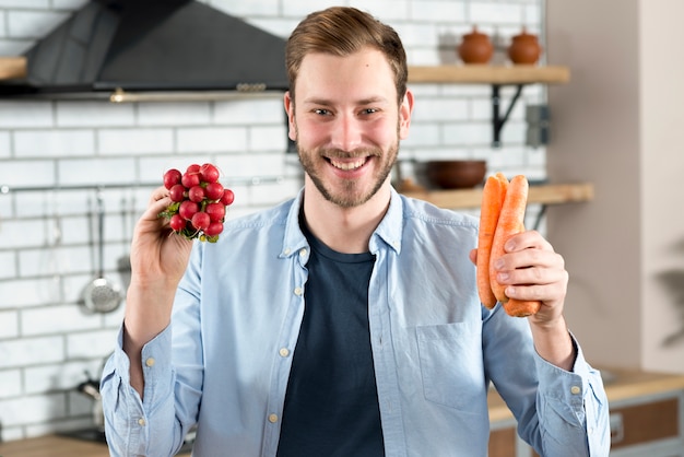 Foto gratuita retrato de hombre joven con nabo rojo y zanahoria naranja