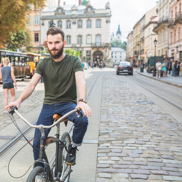 Retrato de un hombre joven que monta la bicicleta en la ciudad