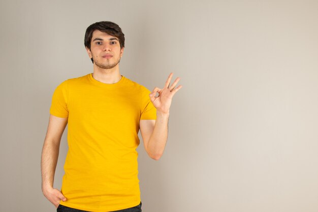 Retrato de un hombre joven que muestra un gesto bien contra el gris.