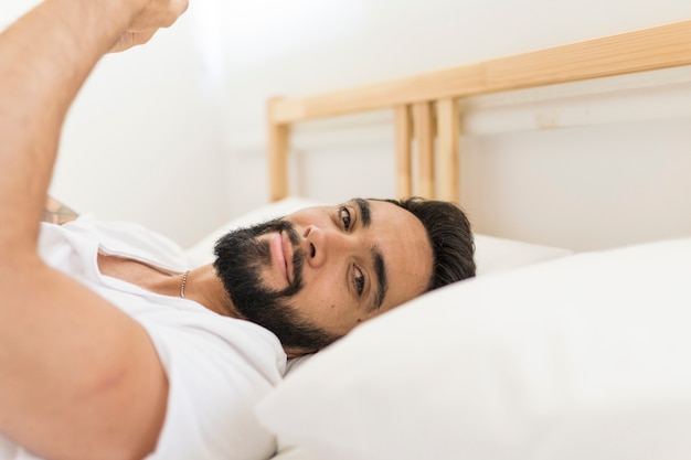 Retrato de un hombre joven que se relaja en cama en dormitorio