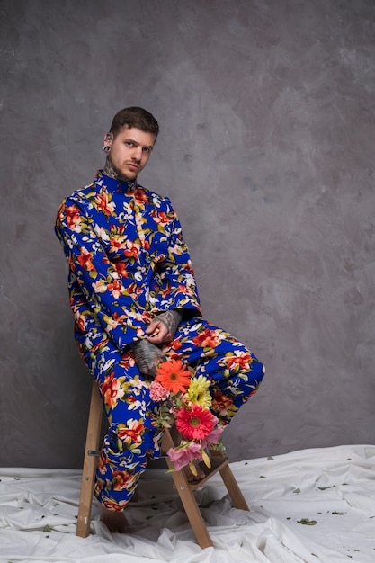 Retrato de un hombre joven que sostiene la flor en las manos mirando a la cámara