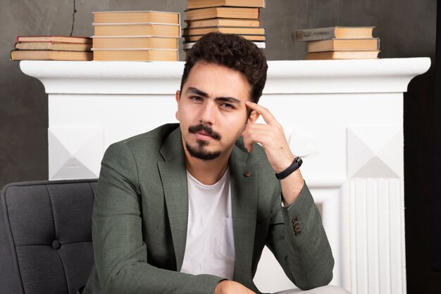 Retrato de hombre joven sentado en una silla pensando.