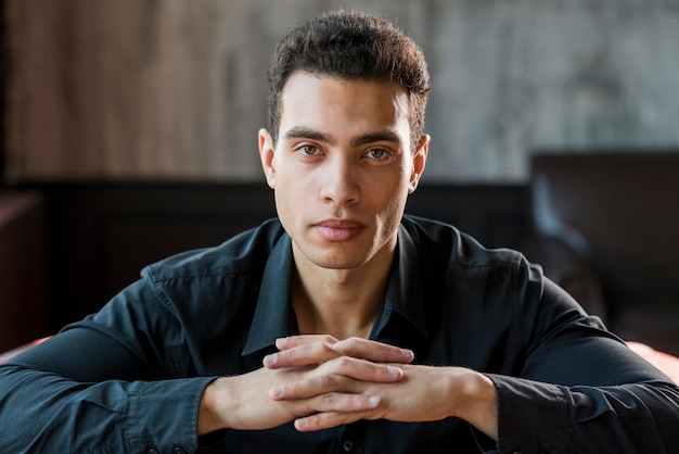 Retrato de un hombre joven serio con la mano apretada mirando a la cámara