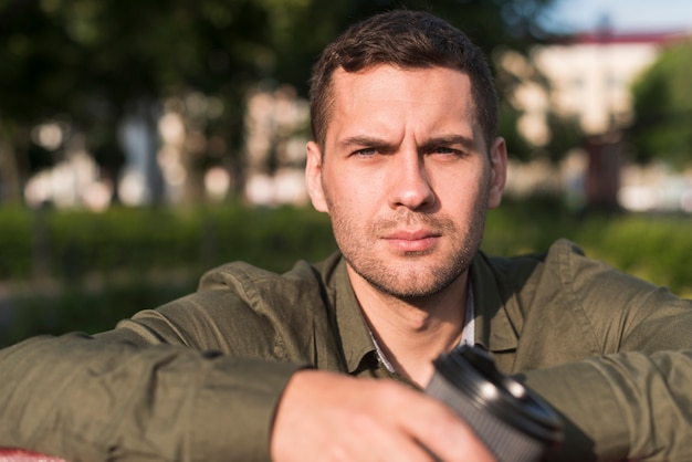 Foto gratuita retrato de hombre joven serio mirando a cámara en el parque