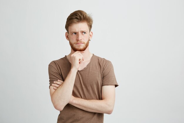 Retrato del hombre joven serio que piensa considerando mirar en lado.