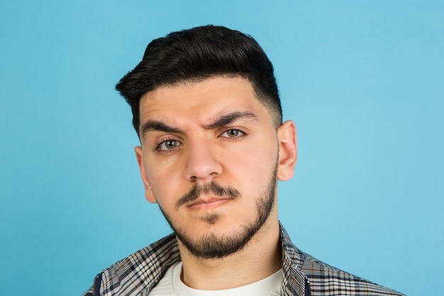 Retrato de hombre joven sobre fondo azul de estudio Concepto de emociones humanas expresión facial anuncio de ventas para jóvenes