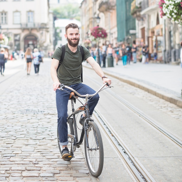 Retrato de un hombre joven sonriente andar en bicicleta al aire libre