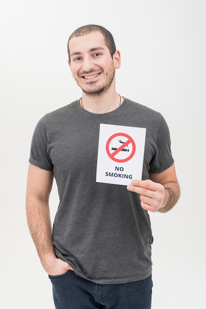 Retrato de un hombre joven sonriente con la mano en el bolsillo que muestra la señal de no fumar