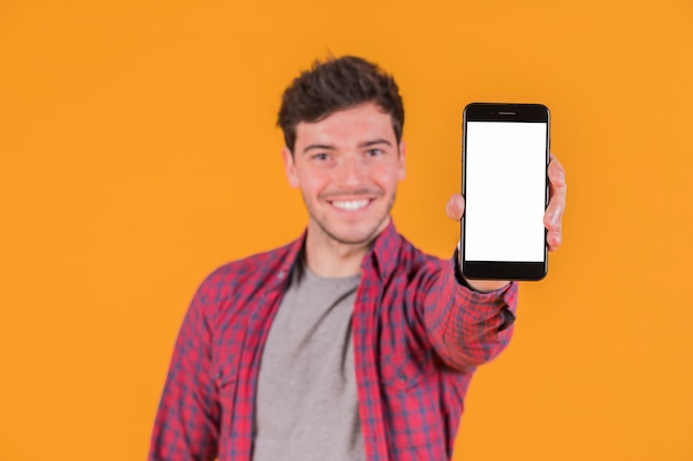 Retrato de un hombre joven sonriente que muestra el teléfono móvil de la pantalla blanca en blanco