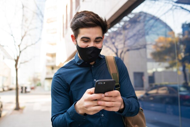 Retrato de hombre joven con su teléfono móvil mientras camina al aire libre en la calle. Nuevo concepto de estilo de vida normal. Concepto urbano.