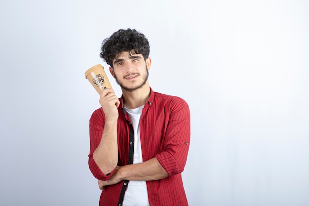 Retrato de hombre joven con taza de café de pie sobre fondo blanco. Foto de alta calidad