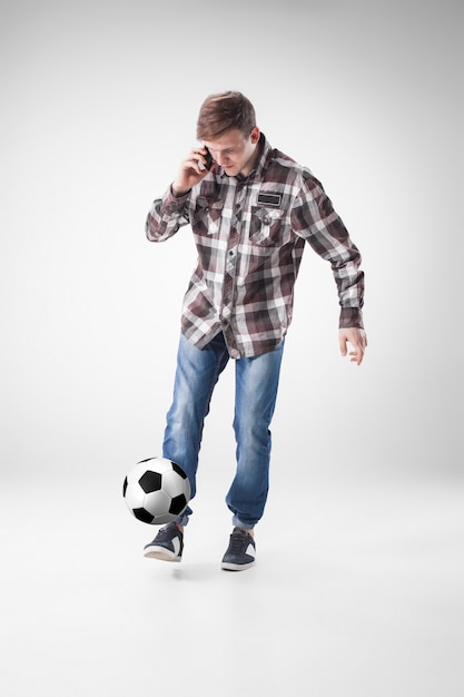 Retrato de hombre joven con teléfono inteligente y pelota de futbol