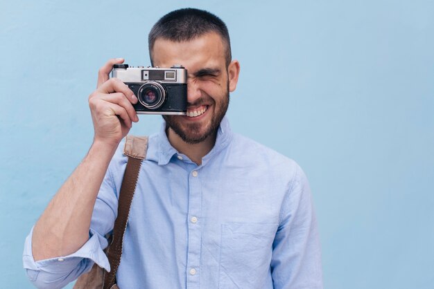 Retrato de hombre joven tomando foto con cámara retro