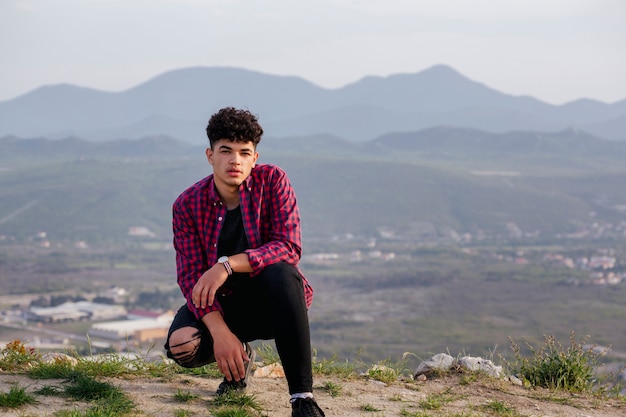 Retrato de hombre joven viajero posando en la colina