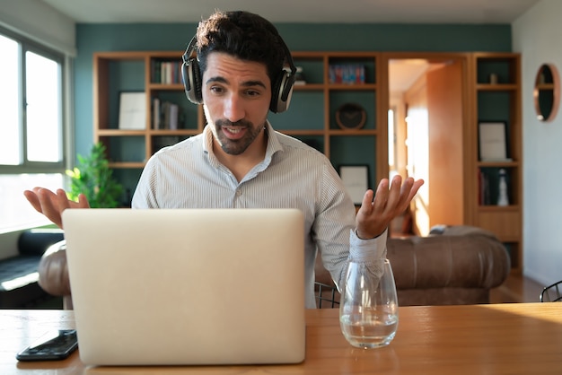 Retrato de hombre joven en una videollamada de trabajo con ordenador portátil desde casa. Concepto de oficina en casa. Nuevo estilo de vida normal.