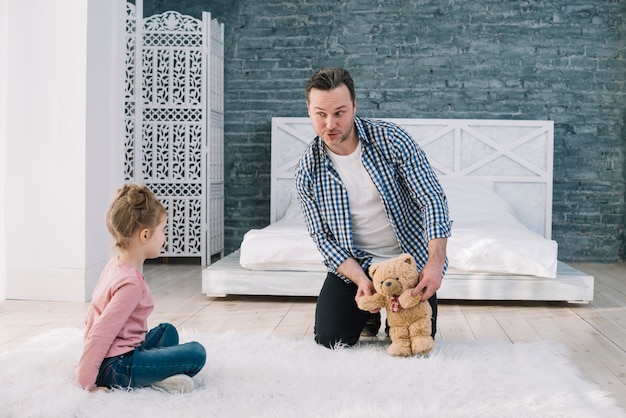 Retrato de hombre jugando con hija en dormitorio