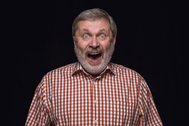 Retrato de hombre mayor aislado sobre fondo negro de estudio de cerca. Photoshot de emociones reales del modelo masculino. Preguntándose, emocionado y asombrado. Expresión facial, concepto de emociones humanas.