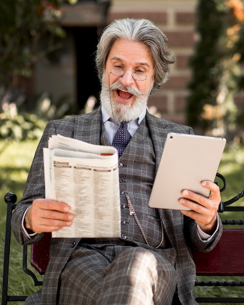 Foto gratuita retrato de hombre mayor barbudo leyendo el periódico