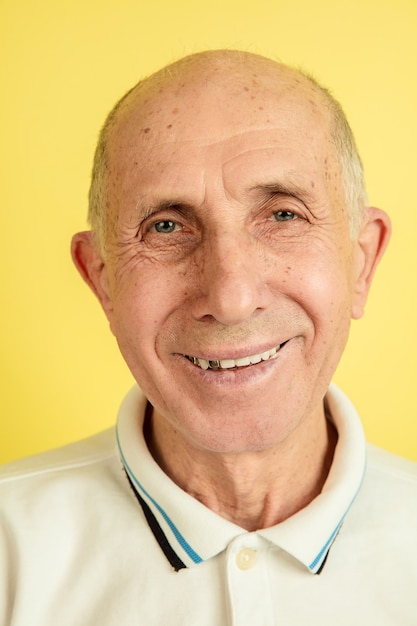 Retrato del hombre mayor caucásico aislado en estudio amarillo