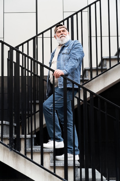 Retrato de hombre mayor posando en las escaleras al aire libre en la ciudad