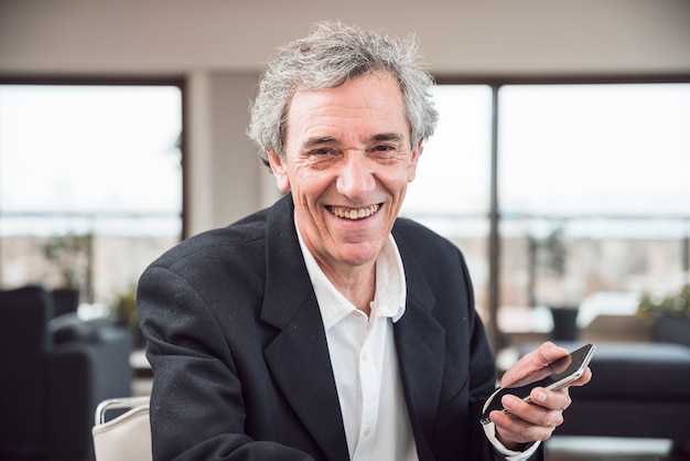 Foto gratuita retrato del hombre mayor sonriente que sostiene el teléfono elegante