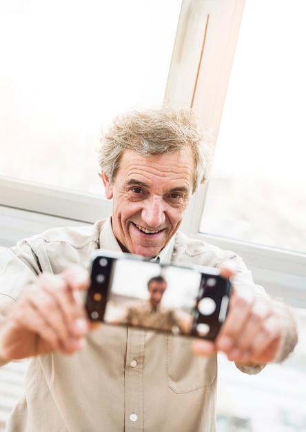 Foto gratuita retrato de hombre mayor sonriente tomando selfie con smartphone