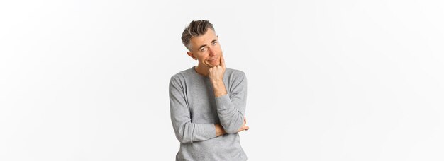 Retrato de un hombre de mediana edad aburrido y sin gracia con suéter gris apoyado en la mano y mirando a la cámara reacio a estar triste sobre fondo blanco