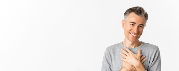 Foto gratuita retrato de un hombre de mediana edad agradecido cogido de la mano en el corazón y sonriendo sintiéndose conmovido y agradecido