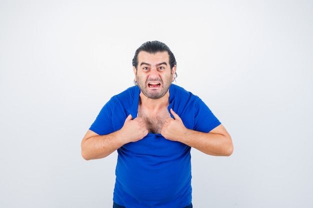 Foto gratuita retrato de hombre de mediana edad rasgando su camiseta con actitud furiosa