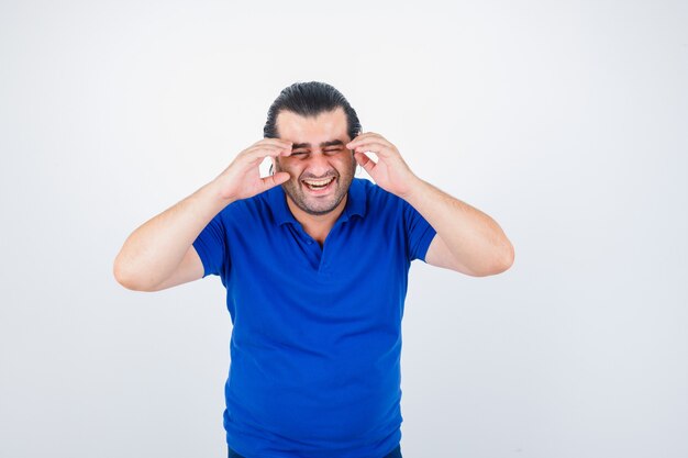 Retrato de hombre de mediana edad riendo mientras sostiene las manos en la cabeza