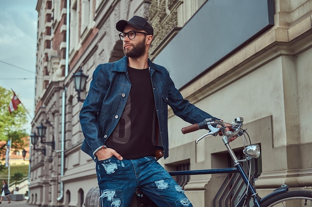 Retrato de un hombre de moda con ropa elegante caminando con bicicleta de ciudad en la calle.
