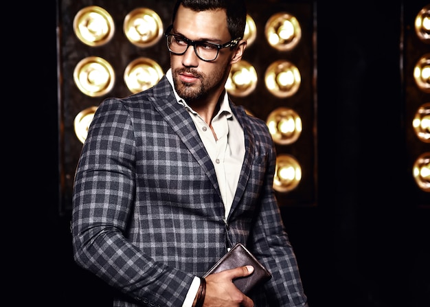 Retrato de hombre de modelo masculino de moda guapo sexy vestido con traje elegante sobre fondo negro de luces de estudio en gafas