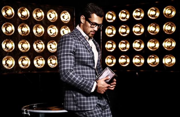 Retrato de hombre de modelo masculino de moda guapo sexy vestido con traje elegante sobre fondo negro de luces de estudio en gafas