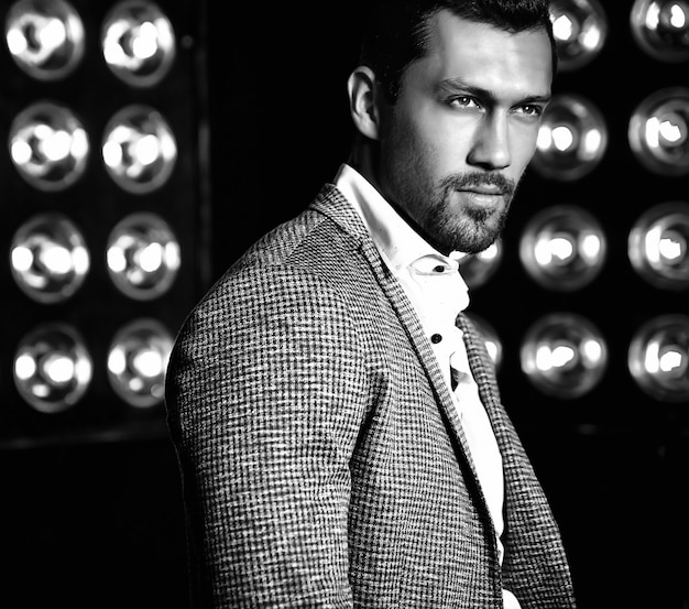 Foto gratuita retrato de hombre de modelo masculino de moda guapo sexy vestido con traje elegante sobre fondo negro de luces de estudio