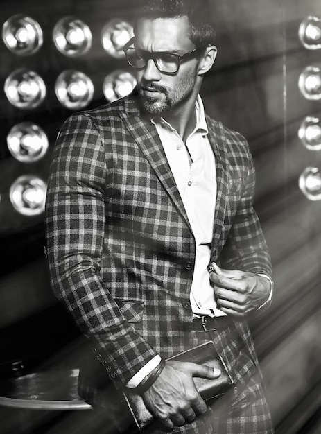 Retrato de hombre de modelo masculino de moda guapo sexy vestido con traje elegante sobre fondo negro de luces de estudio